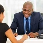 african woman signing a contract at a desk with a african american man sitting across from her