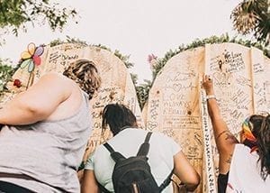 Three ladies writing on a One heart Flower Wall for the vicites of the Pulse night club shooting that happend in Orlando Florida in June 12, 2016