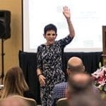 Glenna Hecht with her left hand raised in the air. She was speaking at an SAF event in 2015