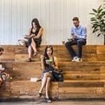 stock image of six people sitting on a teared benches reading or eating