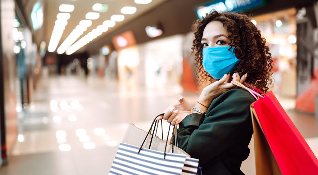 Young woman wearing protection face mask against coronavirus after shopping in the mall. Purchases, shopping, lifestyle concept. Covid-2019.